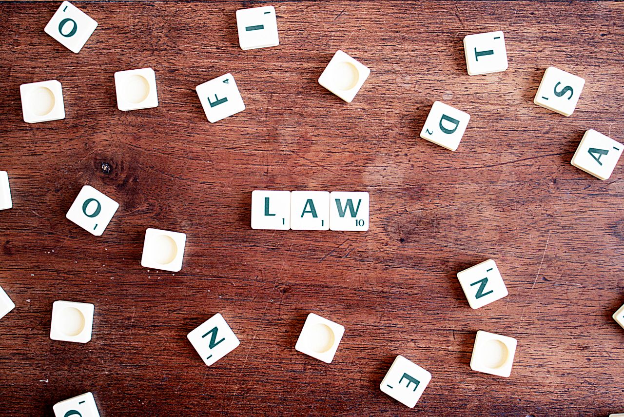 who-we-are Scrabble tiles spelling 'LAW' on a wooden table, symbolizing connections to education and legality.